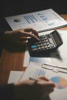 Close up businessman hand using calculator and working with laptop calculate about finance accounting at coffeeshop outdor.finance accounting concept photo