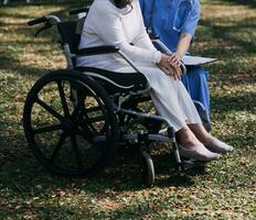 Asian young woman nurse at nursing home take care disabled senior man. Caregiver doctor serve physical therapy for older elderly patient to exercise and practice walking on walker or cane at backyard. photo