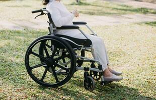 Asian young woman nurse at nursing home take care disabled senior man. Caregiver doctor serve physical therapy for older elderly patient to exercise and practice walking on walker or cane at backyard. photo