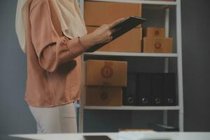 Starting small businesses SME owners female entrepreneurs Write the address on receipt box and check online orders to prepare to pack the boxes, sell to customers, sme business ideas online. photo
