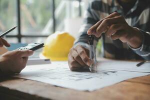 reunión de trabajo en equipo de ingenieros, trabajo de dibujo en la reunión de planos para el trabajo del proyecto con un socio en la construcción de modelos y herramientas de ingeniería en el concepto de sitio de trabajo, construcción y estructura. foto