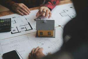 reunión de trabajo en equipo de ingenieros, trabajo de dibujo en la reunión de planos para el trabajo del proyecto con un socio en la construcción de modelos y herramientas de ingeniería en el concepto de sitio de trabajo, construcción y estructura. foto