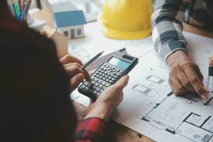 reunión de trabajo en equipo de ingenieros, trabajo de dibujo en la reunión de planos para el trabajo del proyecto con un socio en la construcción de modelos y herramientas de ingeniería en el concepto de sitio de trabajo, construcción y estructura. foto