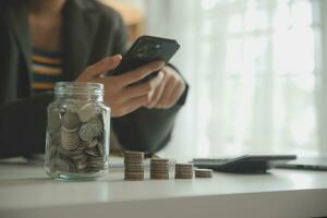 saving money and accounting concept. business man putting coin insert to jar and make acounting book for finance management to investment and saving. photo