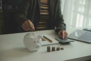 saving money and accounting concept. business man putting coin insert to jar and make acounting book for finance management to investment and saving. photo