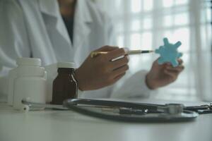 Doctor and patient sitting and talking at medical examination at hospital office, close-up. Therapist filling up medication history records. Medicine and healthcare concept. photo