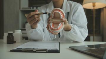 los dentistas están discutiendo problemas dentales al informar la imagen de rayos X en la pantalla del portátil a los pacientes. foto