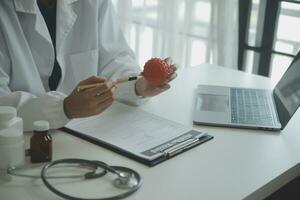 Doctor and patient sitting and talking at medical examination at hospital office, close-up. Therapist filling up medication history records. Medicine and healthcare concept. photo