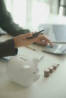 saving money and accounting concept. business man putting coin insert to jar and make acounting book for finance management to investment and saving. photo