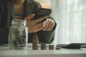 saving money and accounting concept. business man putting coin insert to jar and make acounting book for finance management to investment and saving. photo