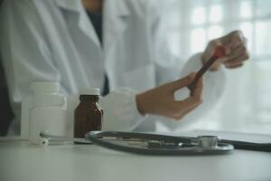 Doctor and patient sitting and talking at medical examination at hospital office, close-up. Therapist filling up medication history records. Medicine and healthcare concept. photo