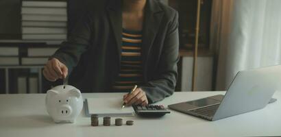 ahorro dinero y contabilidad concepto. negocio hombre poniendo moneda insertar a tarro y hacer contabilidad libro para Finanzas administración a inversión y ahorro. foto