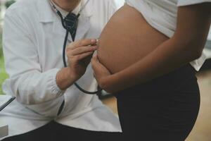 Female doctor is checking pregnant woman with stethoscope. Concept caring for pregnant woman photo