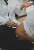 Female doctor is checking pregnant woman with stethoscope. Concept caring for pregnant woman photo