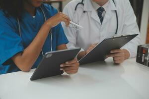 Medical worker in lab coat and sterile mask, doing a microscope analysis while her colleague are working behind photo
