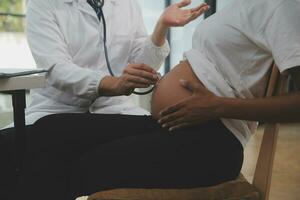 Female doctor is checking pregnant woman with stethoscope. Concept caring for pregnant woman photo