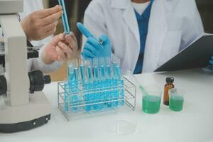 Scientist or medical in lab coat working in biotechnological laboratory, Microscope equipment for research with mixing reagents in glass flask in clinical laboratory. photo