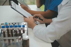 Medical worker in lab coat and sterile mask, doing a microscope analysis while her colleague are working behind photo