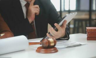 Business and lawyers discussing contract papers with brass scale on desk in office. Law, legal services, advice, justice and law concept picture with film grain effect photo
