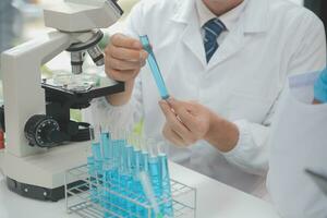 Scientist or medical in lab coat working in biotechnological laboratory, Microscope equipment for research with mixing reagents in glass flask in clinical laboratory. photo