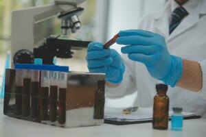 Scientist or medical in lab coat working in biotechnological laboratory, Microscope equipment for research with mixing reagents in glass flask in clinical laboratory. photo