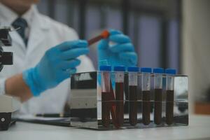 Scientist or medical in lab coat working in biotechnological laboratory, Microscope equipment for research with mixing reagents in glass flask in clinical laboratory. photo