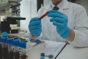 Scientist or medical in lab coat working in biotechnological laboratory, Microscope equipment for research with mixing reagents in glass flask in clinical laboratory. photo