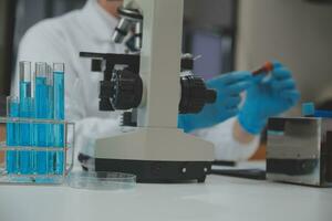 Scientist or medical in lab coat working in biotechnological laboratory, Microscope equipment for research with mixing reagents in glass flask in clinical laboratory. photo