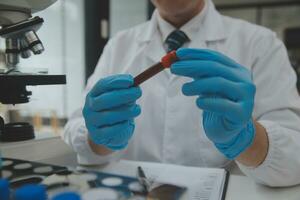 Scientist or medical in lab coat working in biotechnological laboratory, Microscope equipment for research with mixing reagents in glass flask in clinical laboratory. photo
