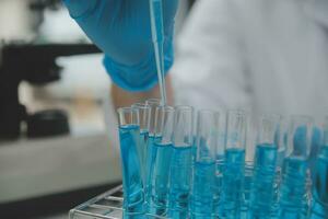 Scientist or medical in lab coat working in biotechnological laboratory, Microscope equipment for research with mixing reagents in glass flask in clinical laboratory. photo