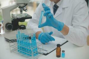 Scientist or medical in lab coat working in biotechnological laboratory, Microscope equipment for research with mixing reagents in glass flask in clinical laboratory. photo