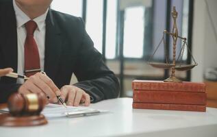 Business and lawyers discussing contract papers with brass scale on desk in office. Law, legal services, advice, justice and law concept picture with film grain effect photo