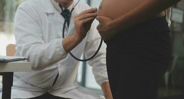 Female doctor is checking pregnant woman with stethoscope. Concept caring for pregnant woman photo