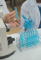Scientist or medical in lab coat working in biotechnological laboratory, Microscope equipment for research with mixing reagents in glass flask in clinical laboratory. photo