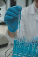 Scientist or medical in lab coat working in biotechnological laboratory, Microscope equipment for research with mixing reagents in glass flask in clinical laboratory. photo