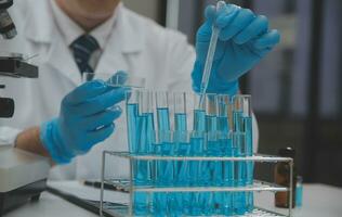 Scientist or medical in lab coat working in biotechnological laboratory, Microscope equipment for research with mixing reagents in glass flask in clinical laboratory. photo