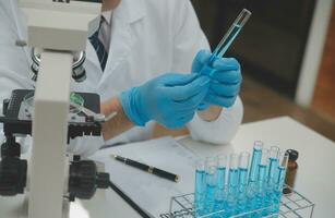 Scientist or medical in lab coat working in biotechnological laboratory, Microscope equipment for research with mixing reagents in glass flask in clinical laboratory. photo