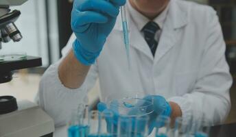 Scientist or medical in lab coat working in biotechnological laboratory, Microscope equipment for research with mixing reagents in glass flask in clinical laboratory. photo