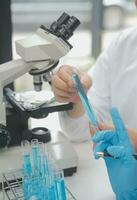 Scientist or medical in lab coat working in biotechnological laboratory, Microscope equipment for research with mixing reagents in glass flask in clinical laboratory. photo