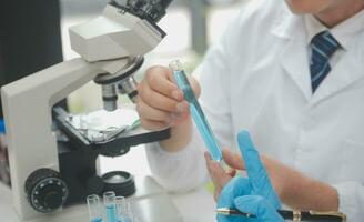 Scientist or medical in lab coat working in biotechnological laboratory, Microscope equipment for research with mixing reagents in glass flask in clinical laboratory. photo