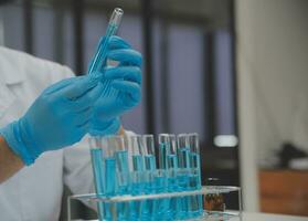 Scientist or medical in lab coat working in biotechnological laboratory, Microscope equipment for research with mixing reagents in glass flask in clinical laboratory. photo