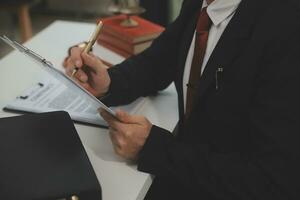 Business and lawyers discussing contract papers with brass scale on desk in office. Law, legal services, advice, justice and law concept picture with film grain effect photo