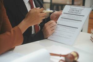 Business and lawyers discussing contract papers with brass scale on desk in office. Law, legal services, advice, justice and law concept picture with film grain effect photo