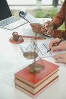 Business and lawyers discussing contract papers with brass scale on desk in office. Law, legal services, advice, justice and law concept picture with film grain effect photo