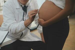 Female doctor is checking pregnant woman with stethoscope. Concept caring for pregnant woman photo