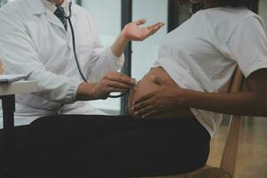 Female doctor is checking pregnant woman with stethoscope. Concept caring for pregnant woman photo