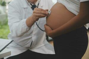 Female doctor is checking pregnant woman with stethoscope. Concept caring for pregnant woman photo