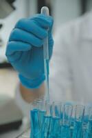 Scientist or medical in lab coat working in biotechnological laboratory, Microscope equipment for research with mixing reagents in glass flask in clinical laboratory. photo