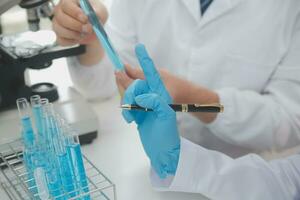 Scientist or medical in lab coat working in biotechnological laboratory, Microscope equipment for research with mixing reagents in glass flask in clinical laboratory. photo