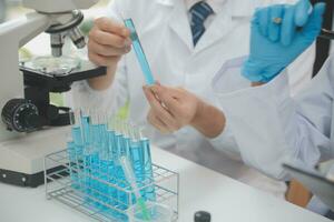 Scientist or medical in lab coat working in biotechnological laboratory, Microscope equipment for research with mixing reagents in glass flask in clinical laboratory. photo